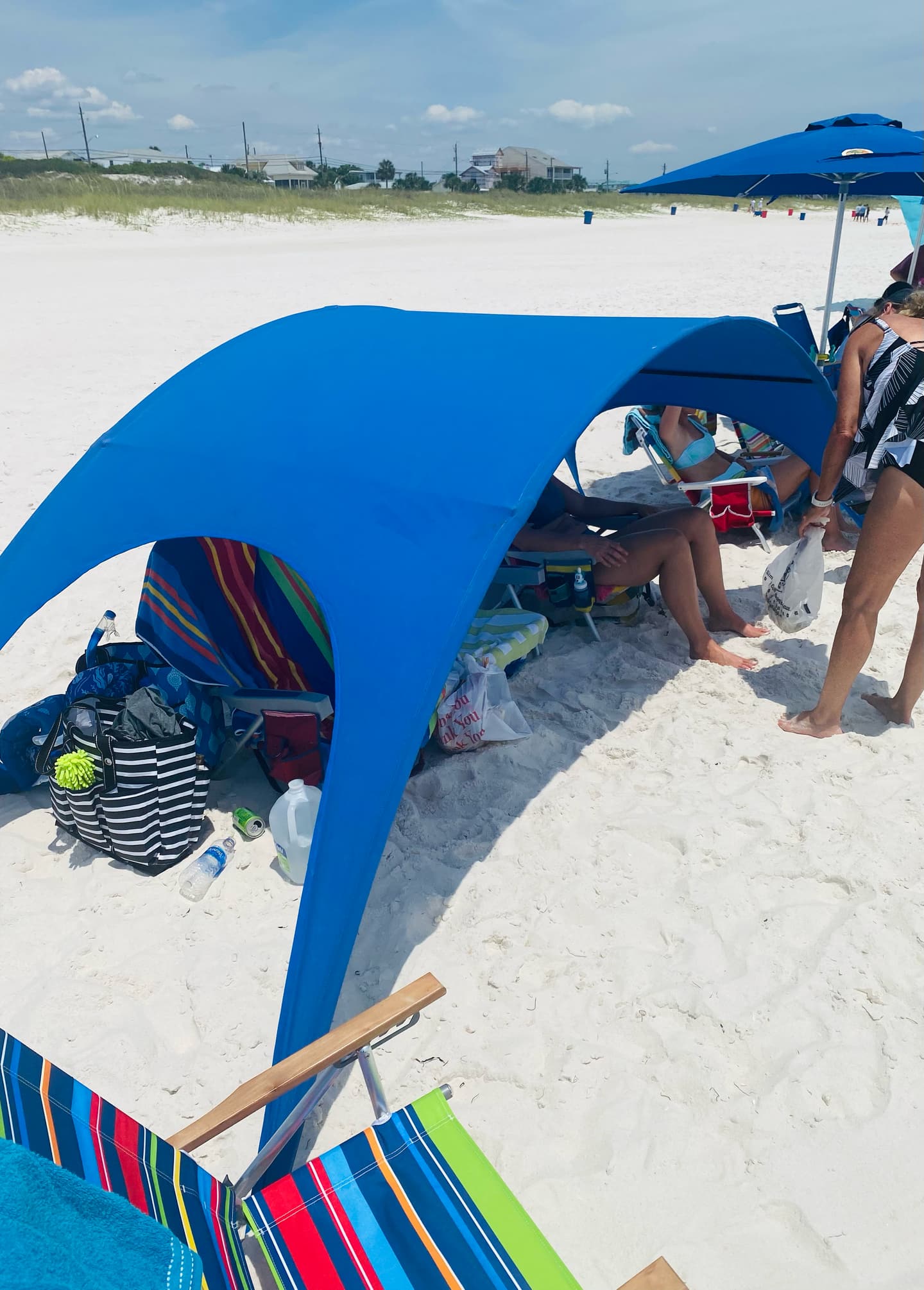 Family under a Shady Baby canopy at the beach on a sunny day