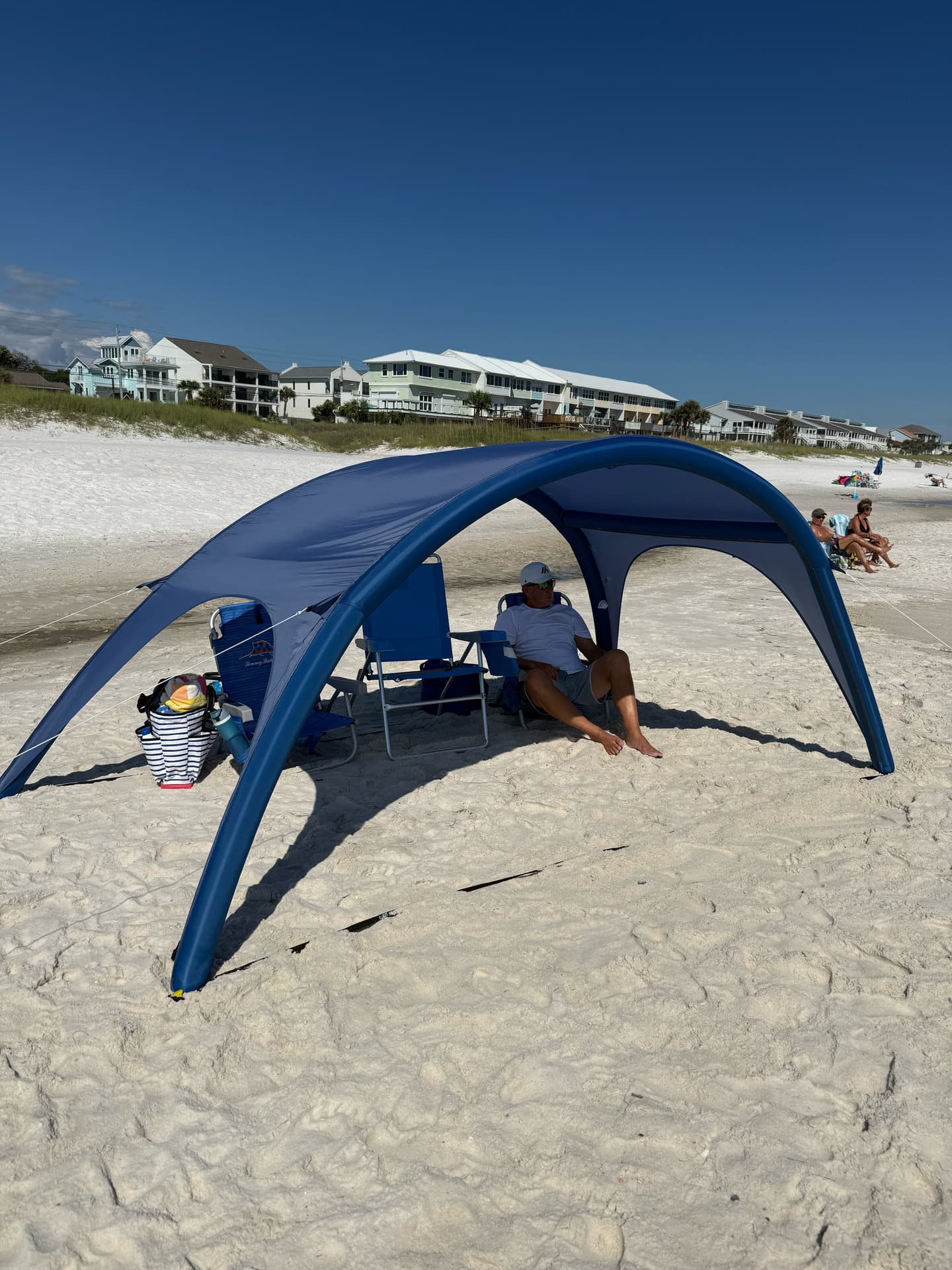 Shady Baby inflatable shade canopy on the beach with a family lounging underneath under blue sky